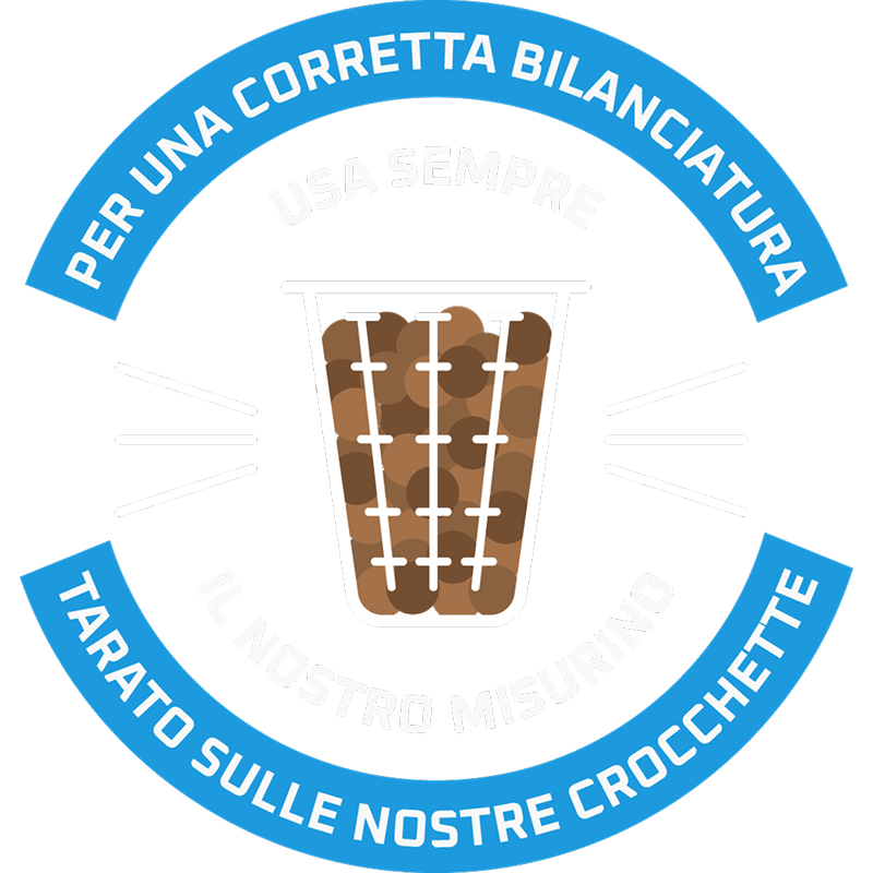 Logo circolare con sfondo blu e testo bianco "Per una corretta bilanciatura – Tarato sulle nostre crocchette", con illustrazione di un misurino graduato pieno di crocchette per cani.